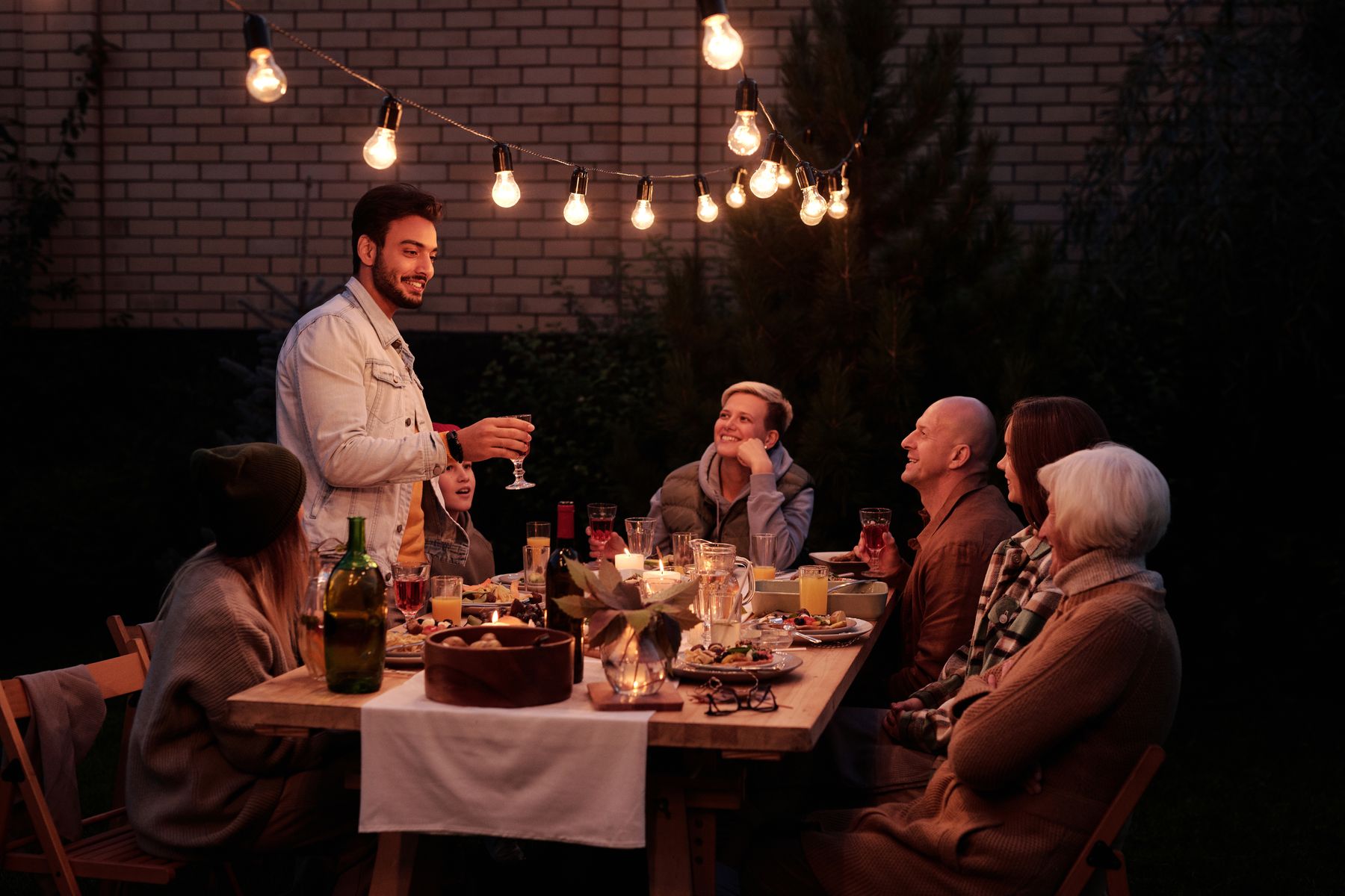 Friends at a long table in a garden under string lights