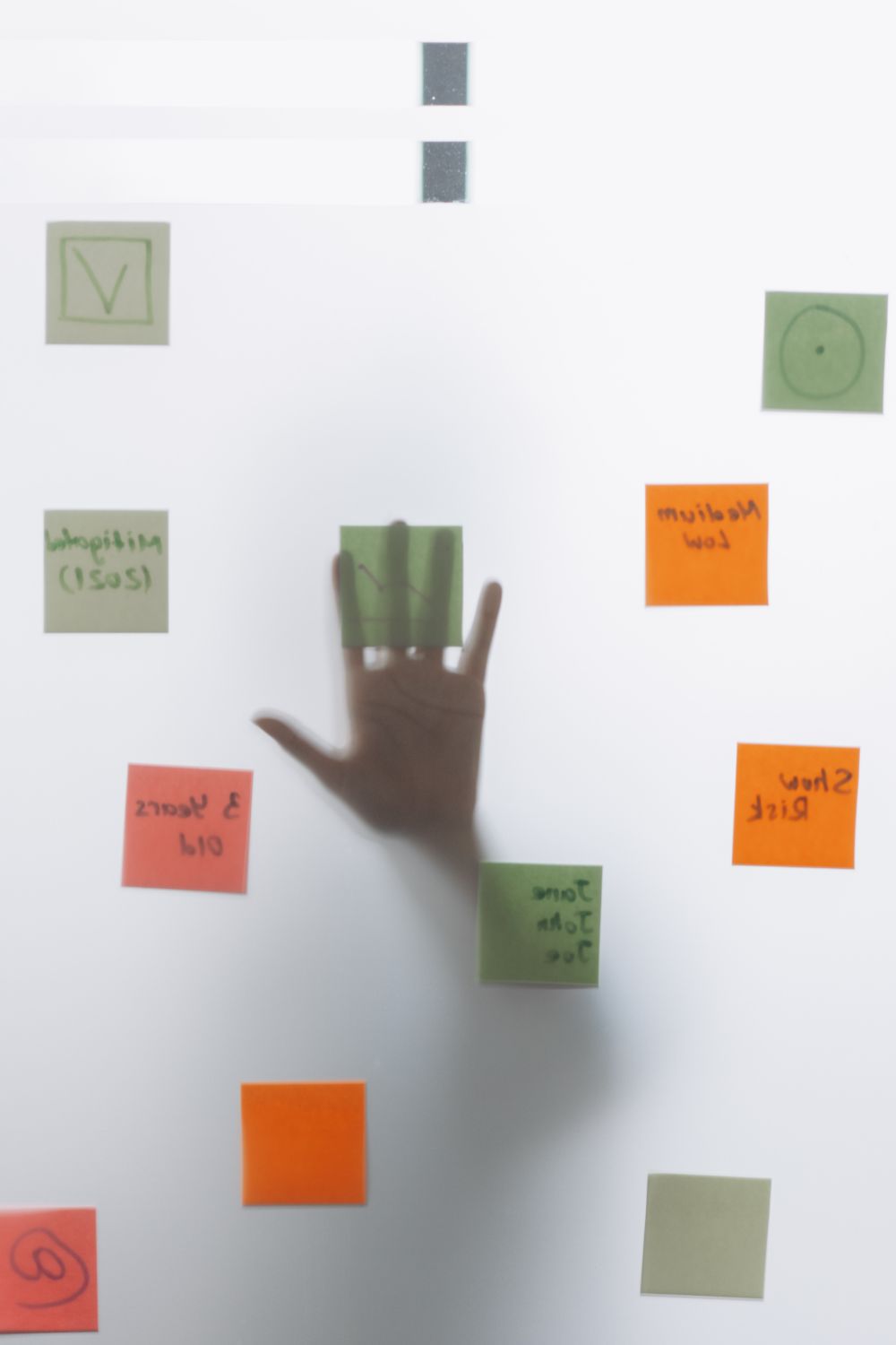 A hand behind a glass wall covered in sticky notes
